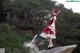 A woman in a red and white dress standing on a rock.