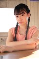 A young woman sitting at a table with her arms crossed.