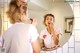 A woman putting on lipstick in front of a mirror.