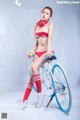 A woman in a red bikini sitting on a blue bike.