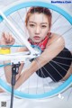 A woman is fixing a bicycle wheel on a white background.