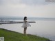 A woman in a white dress standing by the water.