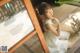 A woman in a white dress sitting on a wooden floor.