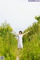 A woman standing in a field with her arms outstretched.