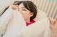 A woman laying in bed under a white sheet.