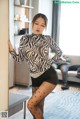 A woman in a zebra print top and black tights posing for the camera.