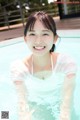 A woman in a white shirt is smiling in a pool.