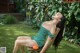 A woman in a green dress sitting on a wooden chair.