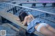 A woman in a white bikini laying on a concrete bench.