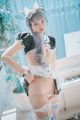 A woman in a maid outfit posing in front of a piano.