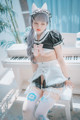 A woman in a maid outfit sitting on a white piano.