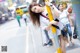 A woman leaning against a yellow pole on a city street.