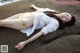 A woman in a white shirt and yellow bikini laying on a rock.