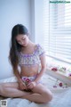 A woman sitting on a bed holding a flower.