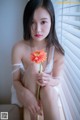 A woman sitting on a window sill holding a flower.