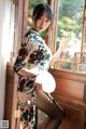 A woman in a cheongsam sitting on a window sill.