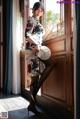 A woman in a cheongsam leaning against a window.