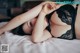 A woman laying on a bed in a black lingerie.