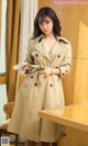 a woman in a trench coat standing next to a table