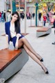 A woman sitting on a bench with her legs crossed.