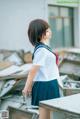 A woman in a school uniform standing in front of a pile of rubble.