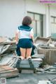 A woman in a school uniform sitting on top of a pile of rubble.