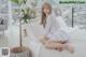 a woman sitting on top of a bed next to a plant