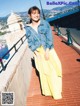 A woman in a yellow skirt and denim jacket posing for a picture.