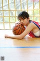 A young woman laying on the floor with a basketball.