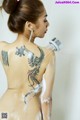 A woman with a tattoo on her back is taking a shower.