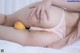 A woman laying on a bed with a peach on her stomach.