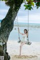 A woman in a white bathing suit sitting on a swing.