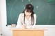 A woman sitting at a desk writing on a piece of paper.