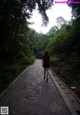 A woman walking down a stone path in the woods.