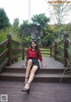 A woman sitting on a wooden bridge with her legs crossed.