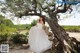 A woman in a wedding dress sitting on a tree.