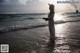 A woman in a white dress and hat standing in the ocean.