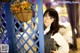 A woman leaning against a blue fence with flowers in a basket.