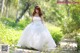 A woman in a wedding dress standing in the woods.