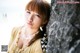 A woman leaning against a stone wall on the beach.