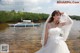 A woman in a wedding dress standing in the water.