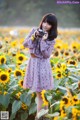 A woman standing in a field of sunflowers holding a camera.