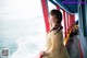 A woman standing on the deck of a boat looking out at the ocean.