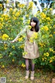 A woman standing in front of a bush of yellow flowers.