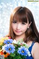 A woman in a blue dress holding a bunch of flowers.