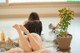 A woman sitting on the floor next to a potted plant.