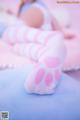 A woman laying on a bed with pink and white striped stockings.