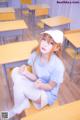 A woman sitting on a desk in a classroom.