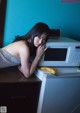 A woman leaning over a microwave with a banana on top of it.