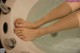 A woman's feet in a bathtub with water on them.